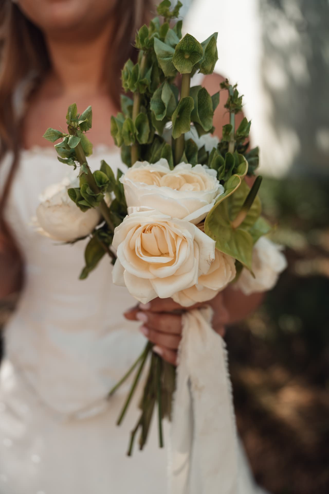 A bride holding a cream rose bouquet